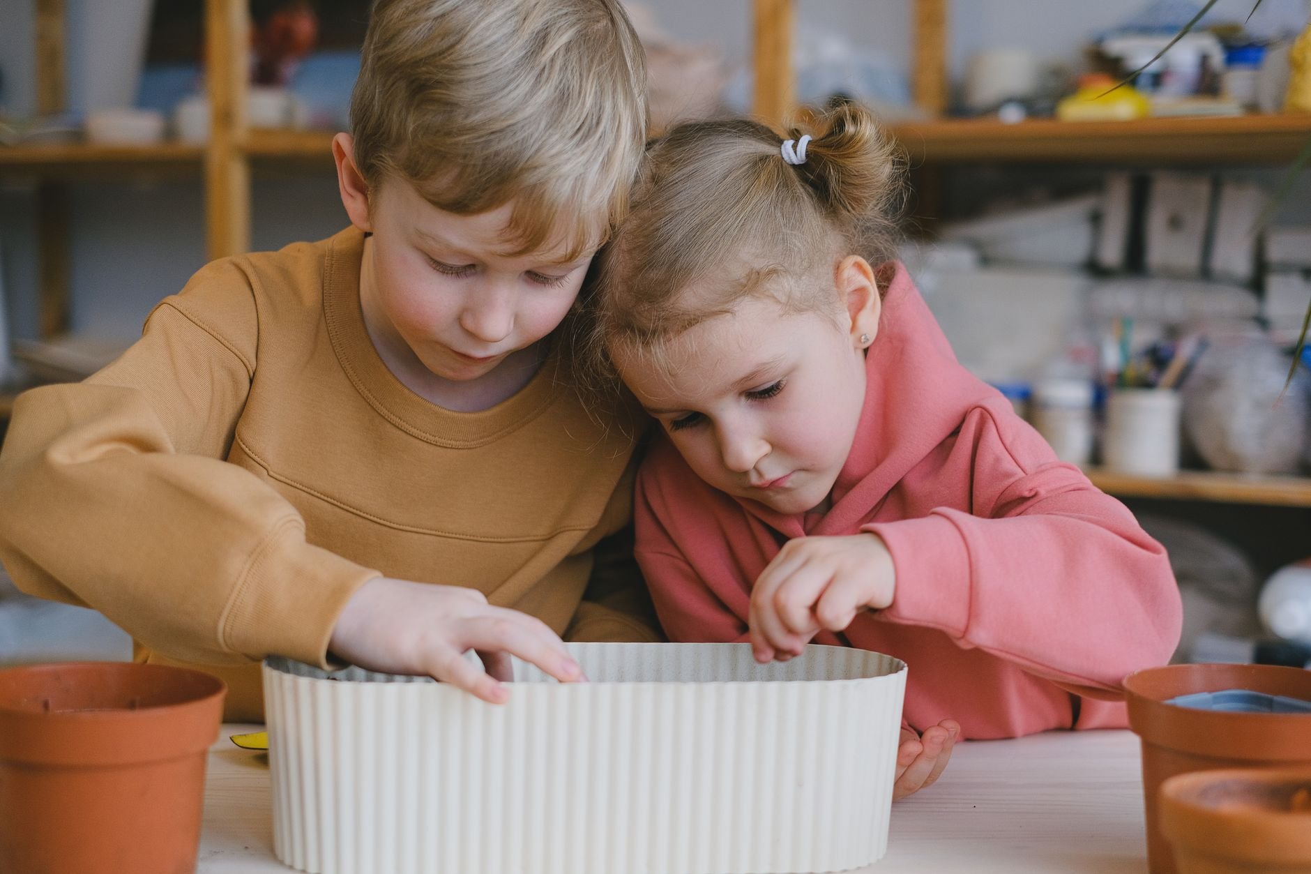 Two children concentrate on a creative indoor play activity, fostering imagination.